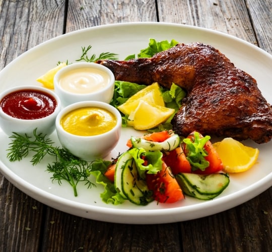 Pierna con muslo de pollo servido junto a una ensalada Pierna con muslo de pollo servido junto a una ensalada