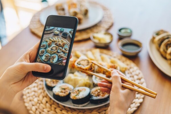 Persona comiendo sushi y viendo el celular Persona comiendo sushi y viendo el celular